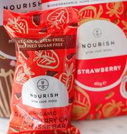 Two Nourish strawberry chocolate mousse bars on a marble surface with a blurred background.