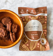 Nourish Organic Cacao Coconut Bites packaging with a bowl of bites on a white background