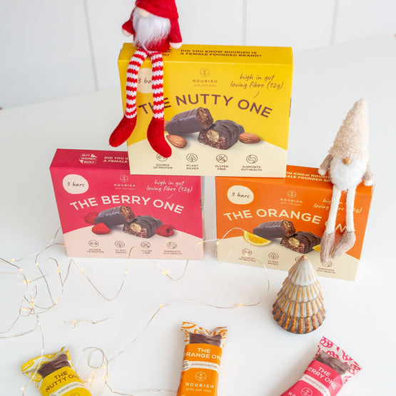 Assorted snack bars with packaging on a white surface, featuring a small elf figure.