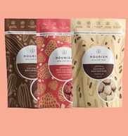 Three packages of Nourish coconut macaroons on a pink background
